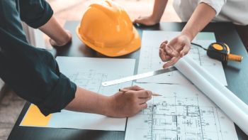 Un maître d'oeuvre et son client consultent les plans d'une maison